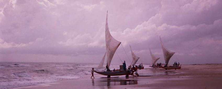 Four Jangadas sitting on the beach next to the water, ready to go.