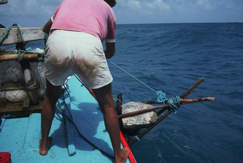 A jangadeiro dropping the stone anchor over the side.