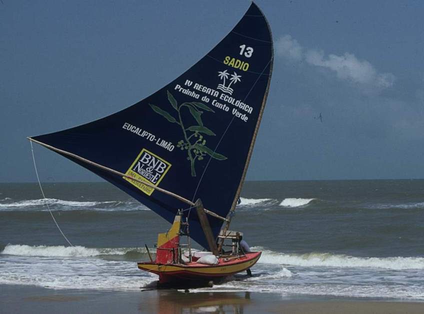 A jangada with a unique blue sail at the tide line, ready to leave.