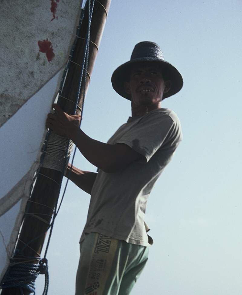 A jangadeiro holding the mast while looking out over the ocean.
