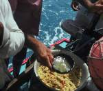 A jangadeiro is adding the caldo (fish broth) to the farinha to make the pirão
