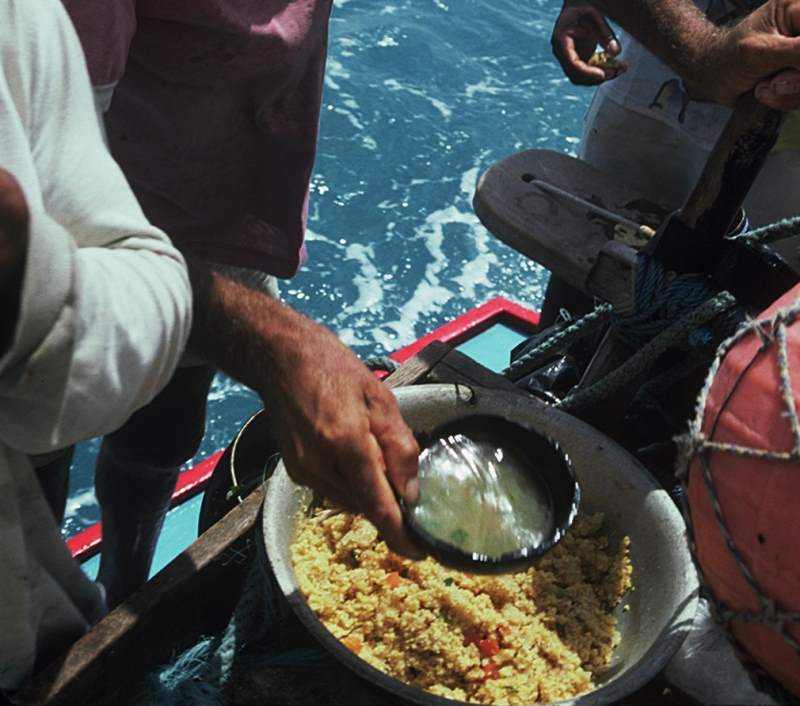A jangadeiro is adding the caldo (fish broth) to the farinha to make the pirão