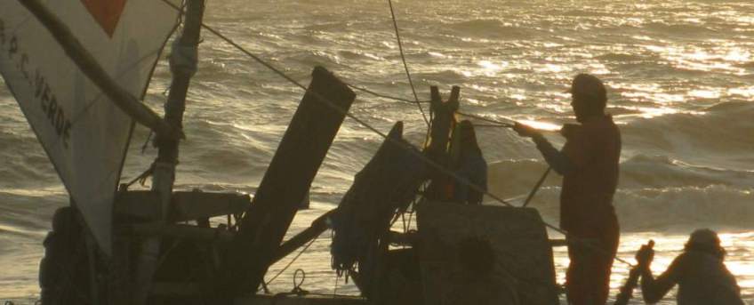 Close up of a jangada in the surf, the captain holding some lines.