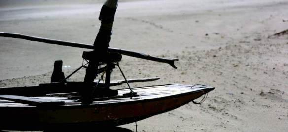 A jangada sitting on the beach with the boom on the tabernacle.
