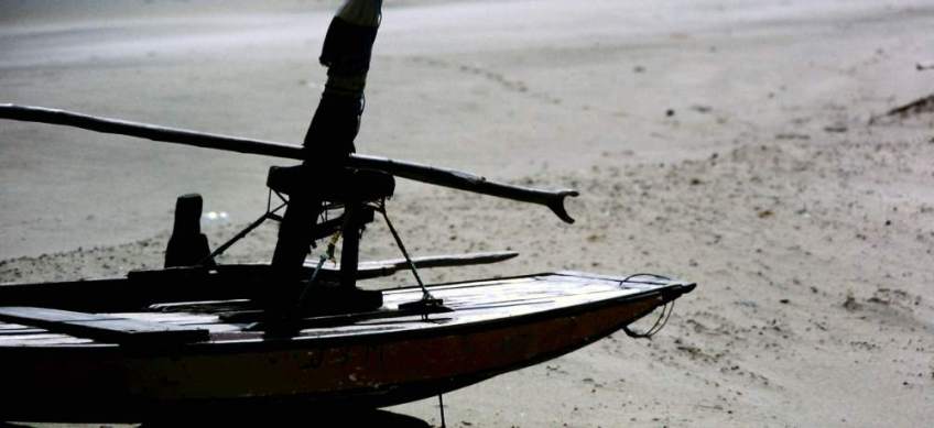 A jangada sitting on the beach with the boom on the tabernacle.