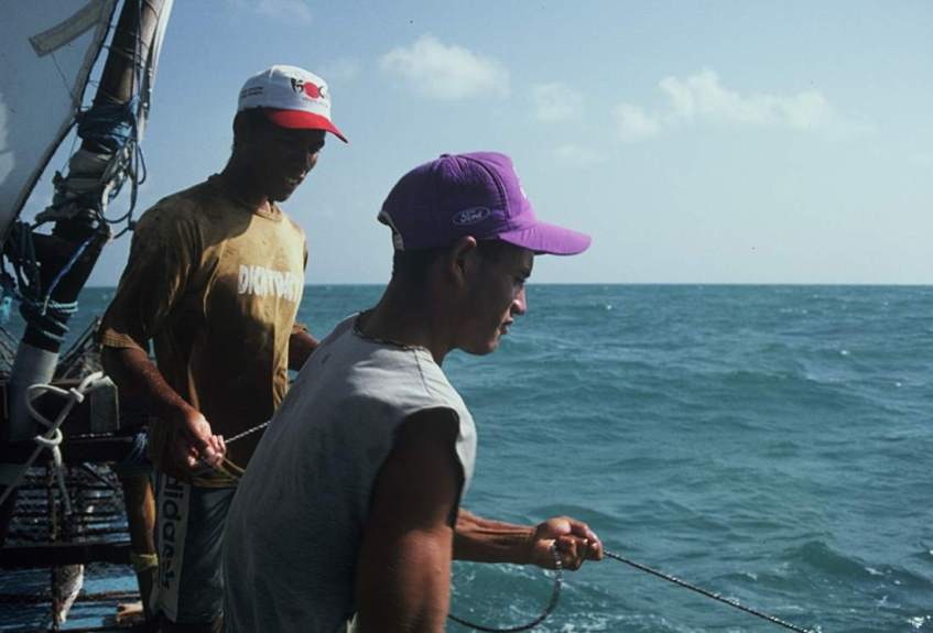 Two jangadeiros pulling up a lobster pot.