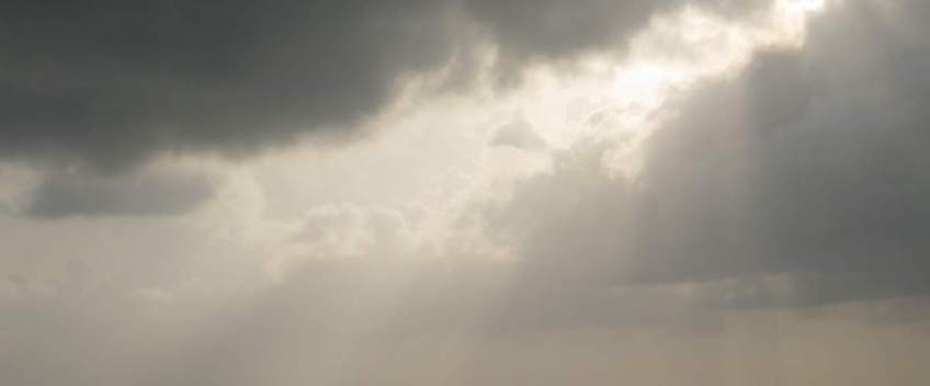 Sky with sun filtering through clouds.