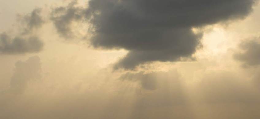 Sky with sun filtering through clouds.