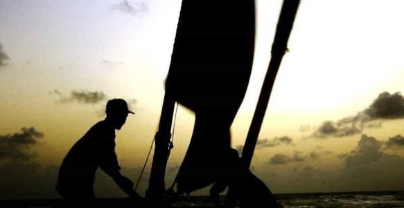 Two jangadeiros setting the sail in the early morning.