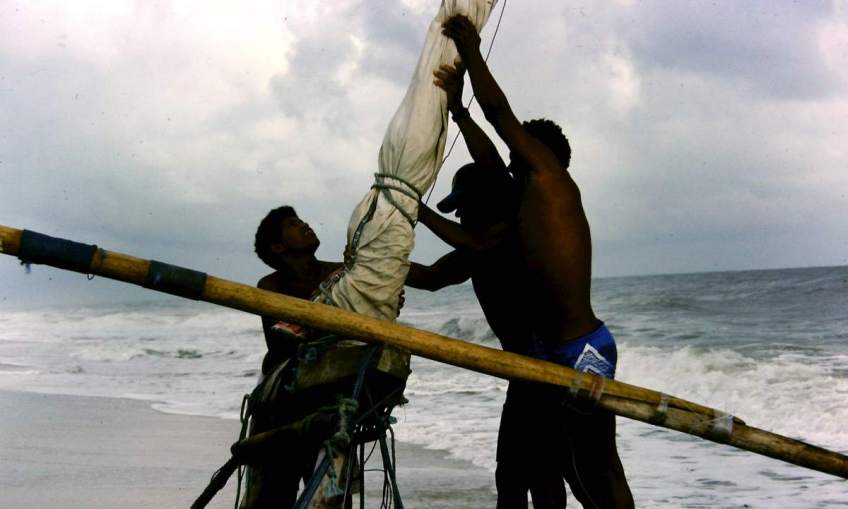 Three jangadeiros raising a jangada's mast.