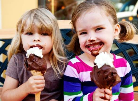 Two young girls eating gelato cones.