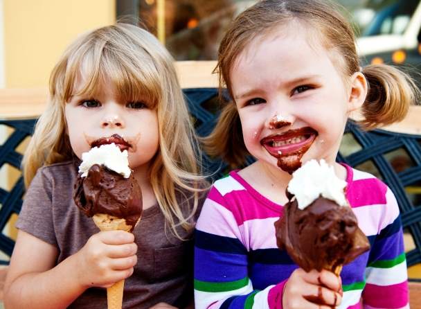 Two young girls eating gelato cones.