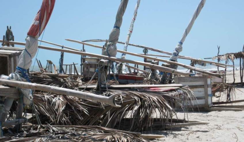 Several jangadas on the beach, their decks covered with palm fronds to protect against the hot sun.