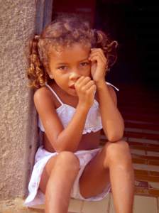 Girl sucking thumb on doorstep.